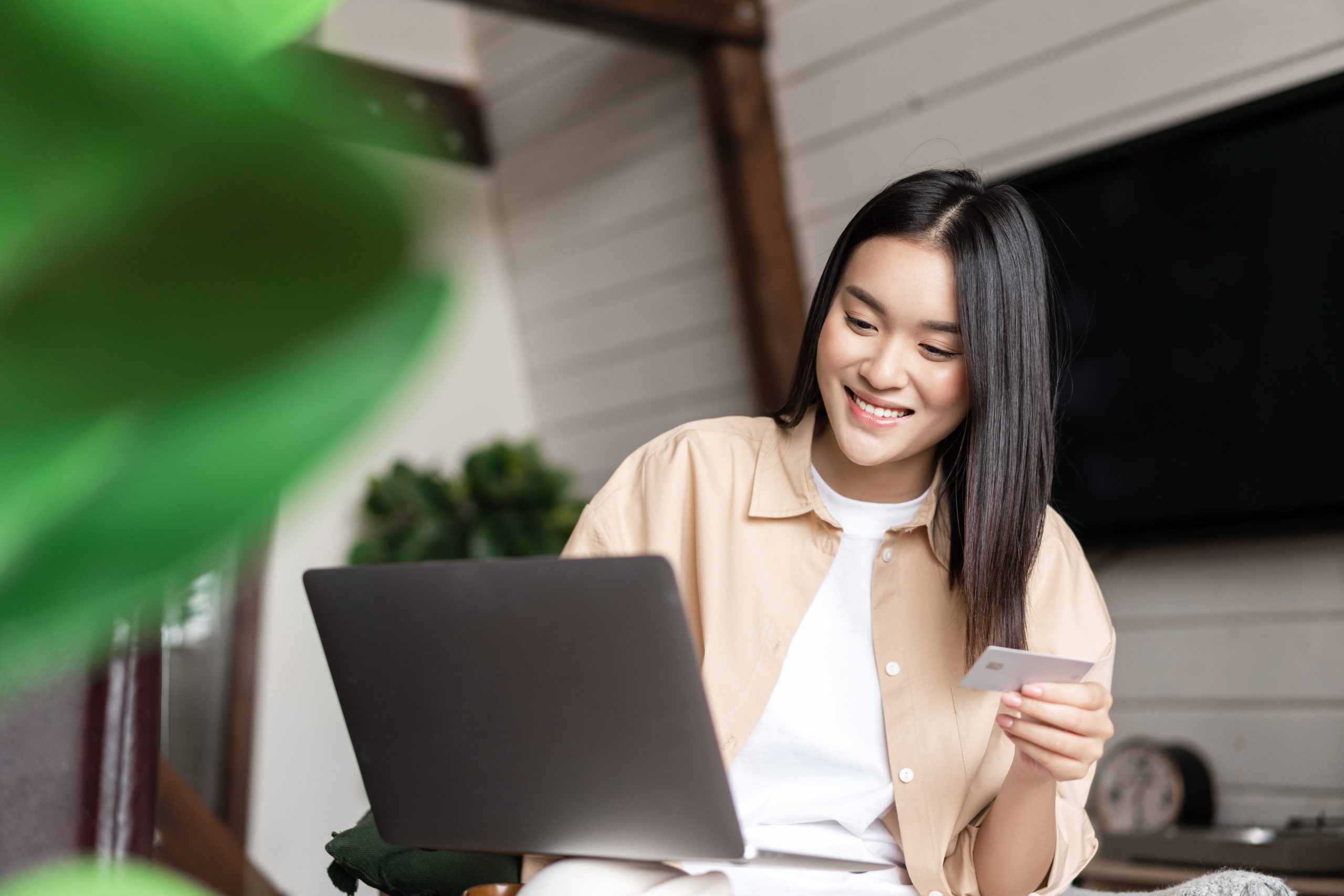 Digital Wholesaling: Simplify ordering for your wholesale customers - Wholesale Suite Woman smiling while holding a credit card and using a laptop